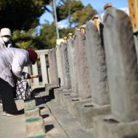 People offer joss ticks to the graves of the 47 ronin samurai at Sengakuji temple in Tokyo on Jan. 8. The 47 ronin, who inspired the long-loved saga of loyalty and honor eulogized in films, books and plays, are fighting a new kind of battle in urban Japan. An apartment complex is going up next to the curved tile-roofed Sengakuji temple where the three-century-old graves of the ronin, or masterless samurai, lie. Condo set to loom over graves of legendary samurai spurs protests