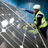 A worker secures a solar panel array at a Sharp Corp. factory in 2011. Panel proposes cutting solar tariff by as much as 16%
