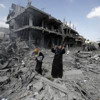 A Palestinian woman pauses amid destroyed buildings in the northern district of Beit Hanun in the Gaza Strip during a humanitarian truce on July 26, 2014. Exhaustive study reveals high civilian death toll in Gaza house strikes