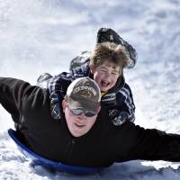 A father and son ride a snow disc down a street Tuesday in Roanoke, Virginia, after a storm blasted the eastern U.S. Icy snowstorm paralyzes eastern United States; more to come
