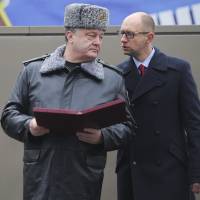 Ukrainian Prime Minister Arseniy Yatsenyuk (right) talks to President Petro Poroshenko during their visit to the national guard’s training center outside Kiev on Friday. Analysis: NATO's expansion is at the root of Ukraine's crisis