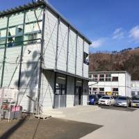 Prefab sprout: Otsuchi Junior High students wave from the window of their temporary school building in the tsunami-hit coastal town of Otsuchi, Iwate Prefecture. Four years on, Tohoku towns still waiting for schools, homes, answers