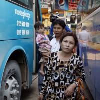 Sam Somaly (front) gets off a bus with her son in-law, Chey Socheat, as he holds her 2-year-old grandson, Be Sokrit, on their arrival at a bus station in Phnom Penh on Feb. 11. Cambodian reality TV show reunites families lost in Khmer Rouge chaos
