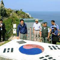 South Korean President Lee Myung Bak touches a representation of his country's national flag during a 2011 trip to disputed islets in the Sea of Japan known by Tokyo as the Takeshima Islands. According to a U.S. documents, Lee was motivated by Japan's inadequate response to the victims of sexual slavery (comfort women). U.S. says 'comfort women' issue was behind Lee's 2012 isle visit