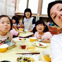 Rikuzentaka Global PR Director Amya Miller (right) eats with children at Yahagi Preschool in Rikuzentakata, Iwate Prefecture, last summer. Putting a foreign face on the 3/11 recovery effort