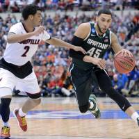 Four horsemen: Michigan State’s Denzel Valentine (right) attempts to get past Louisville’s Quentin Snider during the East regional final on Sunday in Syracuse, New York. The Spartans won 76-70 in overtime to advance to the Final Four. Michigan St. into Final Four