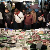 A fishmonger (right) bags fish at Ameya Yokocho market in Tokyo’s Ueno district in March. Households feeling little benefit from higher stocks