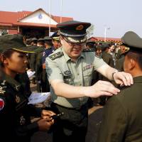 A Chinese military adviser puts rank on Cambodian Army graduates during a graduation ceremony at Army Institute in Cambodia’s Kampong Speu province on March 12. In bid to 'split ASEAN,' China pours money, arms into Cambodian military
