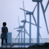 A couple take a stroll past a wind farm in Kamisu, Ibaraki Prefecture, in August 2011. Japan mulls minimum 20% greenhouse gas cut by 2030