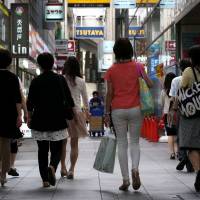 Female shoppers stroll past stores in Kobe on Wednesday. With April household spending unexpectedly slumping and consumer inflation roughly flat, the Bank of Japan’s bet on a steady recovery toward 2 percent inflation is in doubt. Spending slump casts doubt on Bank of Japan optimism