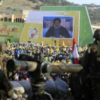 Hezbollah fighters stand guard as Hezbollah leader Sheikh Hassan Nasrallah delivers a speech shown on a screen during a rally commemorating “Liberation Day,” which marks the withdrawal of the Israeli army from southern Lebanon in 2000, in the southern town of Nabatiyeh, Lebanon, Sunday. Nasrallah said Sunday that the region is facing “unprecedented danger” from extremist groups and vowed his militants will expand their involvement in Syria’s civil war in support of government forces. Hezbollah chief admits group fighting on Assad's side across Syria, calls Islamic State threat to world