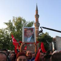A Turk holds up a picture of President Recep Tayyip Erdogan as the Islamist leader addresses a rally in the courtyard of the historic Haci Bayram Mosque in Ankara on Tuesday. Islam takes center stage as Turkish election campaign enters final week