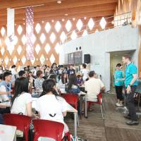 High school children listen to a foreign member of Kinki University's English village explain how to make a bracelet during an open campus program held last July. Tokyo ramps up 'English village' plan as 2020 approaches