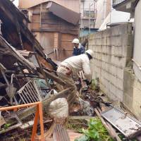 A demolition team goes to work on a derelict house built over 50 years ago. This scene last December in Sumida Ward, Tokyo, could play out more frequently as local authorities obtain new powers to order the removal of empty, collapsing homes. Law for forced demolition of derelict houses takes effect