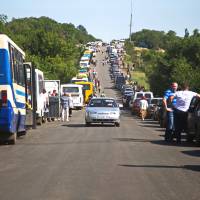 People line up at an Ukrainian checkpoint near Artemivsk, Donetsk region, Thursday. They leave the territory controlled by pro-Russian separatists and go toward the Ukrainian side to buy necessary food, goods and receive pensions. Ukraine's biggest private creditors expressed alarm on Thursday at the pace of their negotiations with cash-strapped Kiev and its escalating threat of a partial debt default. Looming debt default threat alarms Ukraine's creditors
