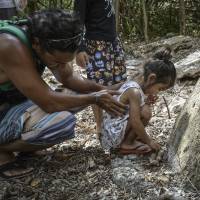Residents of Guam visit the remains of an ancient Chamorro village discovered in the Ritidian area on June 19. The standing rock is the pillar section, or haligi, of a latte stone — a pillar capped by a hemispherical stone with the flat side up — that once formed part of a building's foundation. Accessible ancient Chamorro village found in Guam; some fear it will block U.S. base bringing jobs