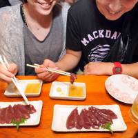 Customers at Aji no Isohei, a traditional Japanese pub in Tokyo's Oimachi district, eat raw pork liver Thursday evening before a new regulation banning it took effect the following day. Raw pork liver fans say goodbye to banned sashimi