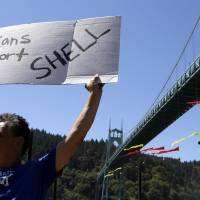 Christopher Anderson, who used to live in Alaska, holds a sign in support of Shell as activists hang from the St. Johns Bridge in an effort to block the Royal Dutch Shell PLC icebreaker Fennica from leaving for Alaska in Portland, Oregon, Thursday. The icebreaker, which is a vital part of Shell’s exploration and spill-response plan off Alaska’s northwest coast, stopped short of the hanging blockade, turned around and sailed back to a dock at the Port of Portland. Protesters in Portland forced away from river after Arctic-bound Shell ship is blocked