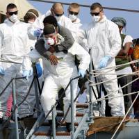 Migrants disembark from the German navy vessel Schleswig Holstein in the Sicilian harbor of Augusta, Italy, on Thursday. Traditionally a nation of emigrants, Italy is now struggling to absorb a ceaseless influx of immigrants from Africa and the Middle East. Inflatable sinks off Libya; 40 migrants feared dead