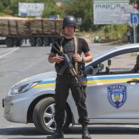 Police officers secure the area near the western Ukrainian city of Mukachevo Sunday, where at least two people were killed Saturday in a gun and grenade attack involving the country's notorious nationalist militia Right Sector, but details of the violence remained confused. Police had surrounded some gunmen in a wooded area of Mukachevo and were trying to negotiate their peaceful surrender, a statement from the regional prosecutor's office said. Ukraine far-right group demands minister's ouster after deadly shootout