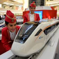 Indonesian models look at scale models of Chinese-made bullet trains during an exhibition at a shopping mall in Jakarta on Aug. 13. China, Japan battle to build Indonesia's first bullet train