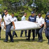 French police officers carry a piece of debris from a plane in Saint-Andre, Reunion Island, last Wednesday. Air safety investigators, one of them a Boeing investigator, have identified the component as a flaperon from the trailing edge of a Boeing 777 wing, a U.S. official said. Flight 370, which disappeared March 8, 2014, with 239 people on board, is the only 777 known to be missing. Barnacles on wing part may help in hunt for MH370