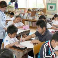 Yoshihiro Matsunami (center right), a teacher at Iwata Elementary School in Toyohashi, Aichi Prefecture, teaches Japanese to non-Japanese children with the help of Filipino and Brazilian counselors. Aichi meets challenge of surge in non-Japanese students