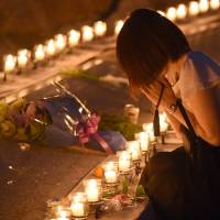 A woman prays for the 1985 Japan Airlines crash victims at a candlelight vigil on Wednesday evening in the village of Ueno, Gunma Prefecture, on the 30th anniversary of the tragedy. Relatives mark 30 years since JAL disaster with trek to mountain crash site