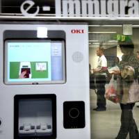 Yō koso: Travelers wait behind a fingerprint reading device at the immigration area of Narita International Airport in Chiba Prefecture. Desperately seeking visas: a mixed bag of queries
