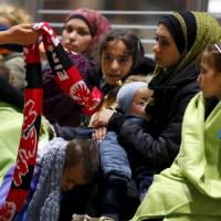 Wellwishers offer warm clothing to Syrians after they arrived on a train from Budapest's Keleti station at the railway station of the airport in Frankfurt, Germany, early Sunday. Austria and Germany threw open their borders to thousands of exhausted migrants on Saturday, bussed to the Hungarian border by a right-wing government that had tried to stop them but was overwhelmed by the sheer numbers reaching Europe's frontiers. Many of the migrants coming into Hungary are discarding identity papers before they cross the frontier in oder to pass themselves off as Syrians, who, because they are fleeing war, have an easier time qualifying to asylum in the EU as refugees. Balkan route migrants shedding ID papers, claiming to be Syrian to qualify as refugees
