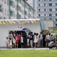 People queue up at a kiosk in Pyongyang on Aug. 16. Street stalls that offer North Koreans a place to spend — or make — money on everything from snow cones to DVDs are flourishing in Pyongyang and other cities in the reclusive country. Street stalls show shifting face of North Korean economy