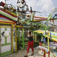 Alyssa Kelley looks over Hamtramck’s Disneyland in Hamtramck, Michigan, on July 29. A retired autoworker spent two decades building his backyard folk art display of brightly painted ceiling fans, rocking horses and plastic Santas that he called “Hamtramck’s Disneyland.” But since Dmytro Szylak’s death this year at age 92, the lights are dimmed and sounds quieted around the whimsical array behind the two homes he owned in the small city surrounded by Detroit. Artist's death at 92 leaves Hamtramck 'Disneyland' future uncertain, in legal limbo