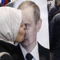 A Syrian woman kisses a poster of Russian President Vladimir Putin during a 2012 pro-Syrian government protest in front of the Russian Embassy in Damascus. In ramping up its military involvement in Syria’s civil war, Russia appears to be betting that the West, horrified by Islamic State’s atrocities, may be willing to tolerate Syrian President Bashar Assad for a while, perhaps as part of a transition. Russian forces are meanwhile apparently being sent to parts of Syria. U.S. uncertain of Moscow's intent as Russia deploys tanks to Syria airfield