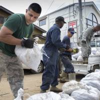 Volunteers from the U.S. military's 374th Civil Engineer Squadron unload bags of mud from a truck in Kanuma, Tochigi Prefecture, on Tuesday. The military said 60 troops and civilians helped shovel flood-related mud from homes in the area. Fresh rain brings more misery to flood-hit Joso
