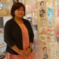 Haruka Imatoku, owner of the Nijiiro Komachi craft store in Tokyo's Kichijoji district, poses for a photo. Some of the postcards on the wall feature rainbow colors. Tokyo craft store meets demand for LGBT rainbow goods hard to find in Japan