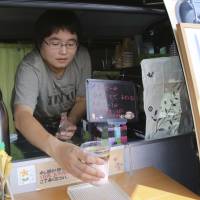 Barista Yukiko Takano, 43, who runs a mobile cafe, serves a cup of latte Friday from her vehicle near the town hall in Naraha, Fukushima Prefecture. This past weekend, Naraha became the first of seven towns that had been entirely evacuated to reopen since the March 11, 2011, disaster, when tsunami slammed into the Fukushima No. 1 nuclear power plant, causing meltdowns and massive radiation leaks. Under radioactive shadow of Fukushima, town of Naraha tries to come back to life