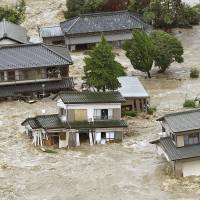 People await rescue on balconies as a torrent threatens to rip their homes from beneath them. The Kinugawa River burst its banks in Joso, Ibaraki Prefecture, on Thursday, with aerial images showing that a levee-like embankment had given way. Storm flood rips through residential neighborhood; helicopters pull survivors from collapsing homes