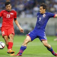 Shinji Okazaki vies for the ball against Singapore's Muhammad Zulfahmi Bin Mohd Arifin (left) during their 2018 World Cup qualifier on June 16, 2015. Okazaki ready to help Japan unleash scoring barrage against Cambodia