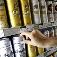Beer by brewers such as Asahi, Kirin and Suntory awaits sale in a cooler at a store in Tokyo on Thursday. SABMiller, AB InBev merger may reignite Japanese brewers' foreign ambitions