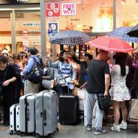 Chinese travelers prepare to shop in Tokyo’s Ginza district on Thursday. They arrived aboard a tour bus. High-end Tokyo stores cash in on China's weeklong holiday