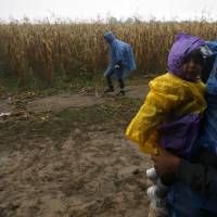 A group of migrants heads to cross a border line between Serbia and Croatia, near the village of Berkasovo, about 100 km west from Belgrade, Tuesday. Refugees from countries such as Syria, Iraq and Eritrea are used to warm climate without sudden weather changes. The majority now passing through the Balkans started their months-long journeys in the summer. Balkan chill sets in as ill-prepared refugees from warm climes shiver in despair
