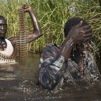 Rebel soldiers patrol and protect civilians in 2014 from the Nuer ethnic group as the civilians walk through flooded areas to reach a makeshift camp for the displaced situated in the United Nations Mission in South Sudan (UNMISS) base in the town of Bentiu, South Sudan. Sides in South Sudan's civil war committed atrocities, cannibalism: AU probe