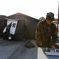 Ground Self-Defense Force soldiers watch over bathing tents at an evacuation center in Koriyama, Fukushima Prefecture, on April 12, 2011, a month after the March 11 earthquake and tsunami triggered a triple meltdown on the Pacific coast. Nearly 40% of Fukushima evacuation personnel exposed to over 1 millisievert