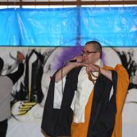 Spitting dharma: Hoodie Monk Gomyo raps as a graffiti artist works in the background at the Yugasan Rendaiji Temple in Okayama Prefecture during Eitai Kuyo, an annual service held to honor the dead. Hoodie Monks mix beats with their Buddhism