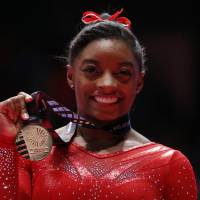 Simone Biles displays her gold medal after winning the women’s all-around final at the World Gymnastics Championships in Glasgow, Scotland, on Thursday. Biles captures all-around title again