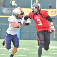 Fujitsu Frontiers quarterback Colby Cameron (right) uses a stiff arm to avoid a tackle by Obic Seagulls linebacker Naoki Kosho during their X League game on Saturday at Fujitsu Stadium Kawasaki. The Frontiers defeated the Seagulls 41-7. Cameron, Fujitsu trounce Obic