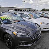 A car salesman works the telephone while searching through inventory at the certified used car lot at Brandon Ford in Brandon, Florida. on Tuesday. Sales of new cars and trucks rose by double-digit percentages at most major automakers in October, and companies are raising their expectations for the rest of the year. GM boasts best sales since 2000 as U.S. strength lifts carmakers; rate hike argument grows