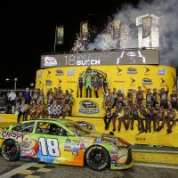 Kyle Busch raises his trophy after winning the NASCAR Sprint Cup Series auto race and the season title Sunday at Homestead-Miami Speedway in Homestead, Florida. Via Nascar and champ Busch, Toyota targeted red, white and blue fans and reaped loyalty green