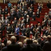 French lawmakers observe a minute of silence a day after deadly bomb attack on a presidential guard bus in Tunis that killed at least 12 people, prior to a session of questions to the Government at the French National Assembly in Paris on Wednesday. French lawmakers vote 515 to 4 to extend Islamic State-targeted airstrikes in Syria