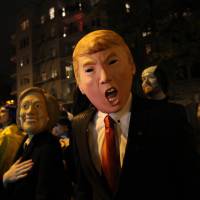David Jiang, wearing a Donald Trump mask, and his girlfriend, Kaja Klupinska (left), wearing a Hillary Rodham Clinton mask, make their way up Sixth Avenue during the Greenwich Village Halloween Parade Saturday in New York. Trump, Hillary, bacon as Big Apple put on its Halloween face
